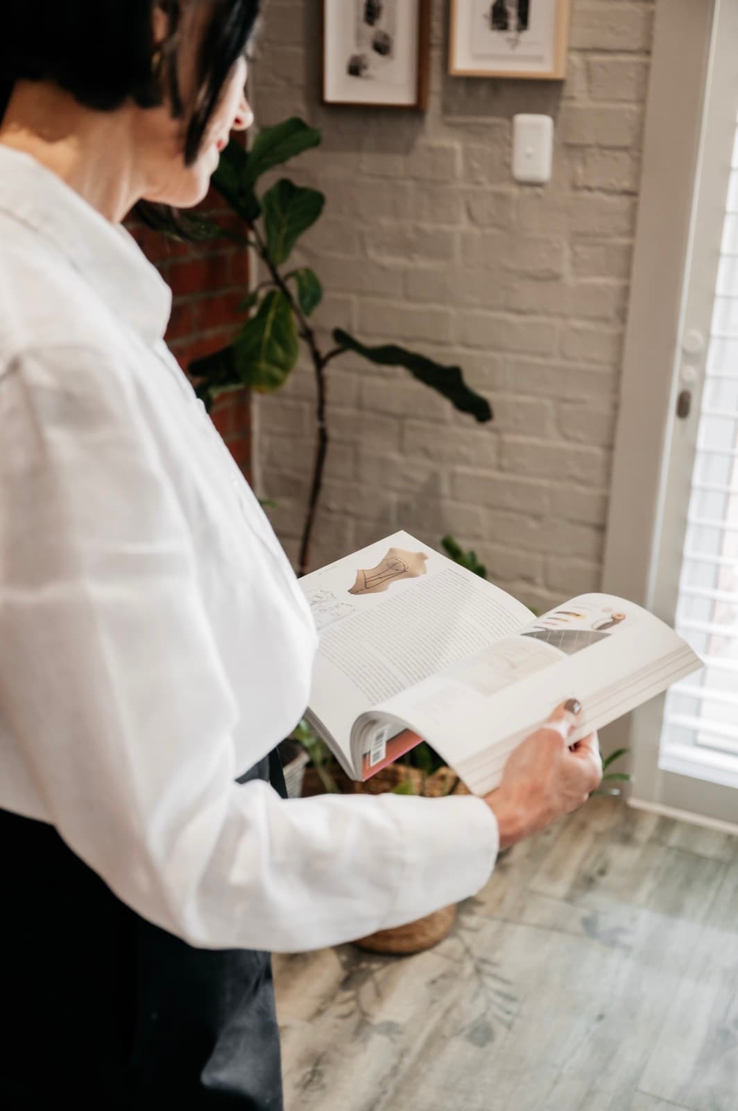 Belinda reading an open workbook at the studio counter