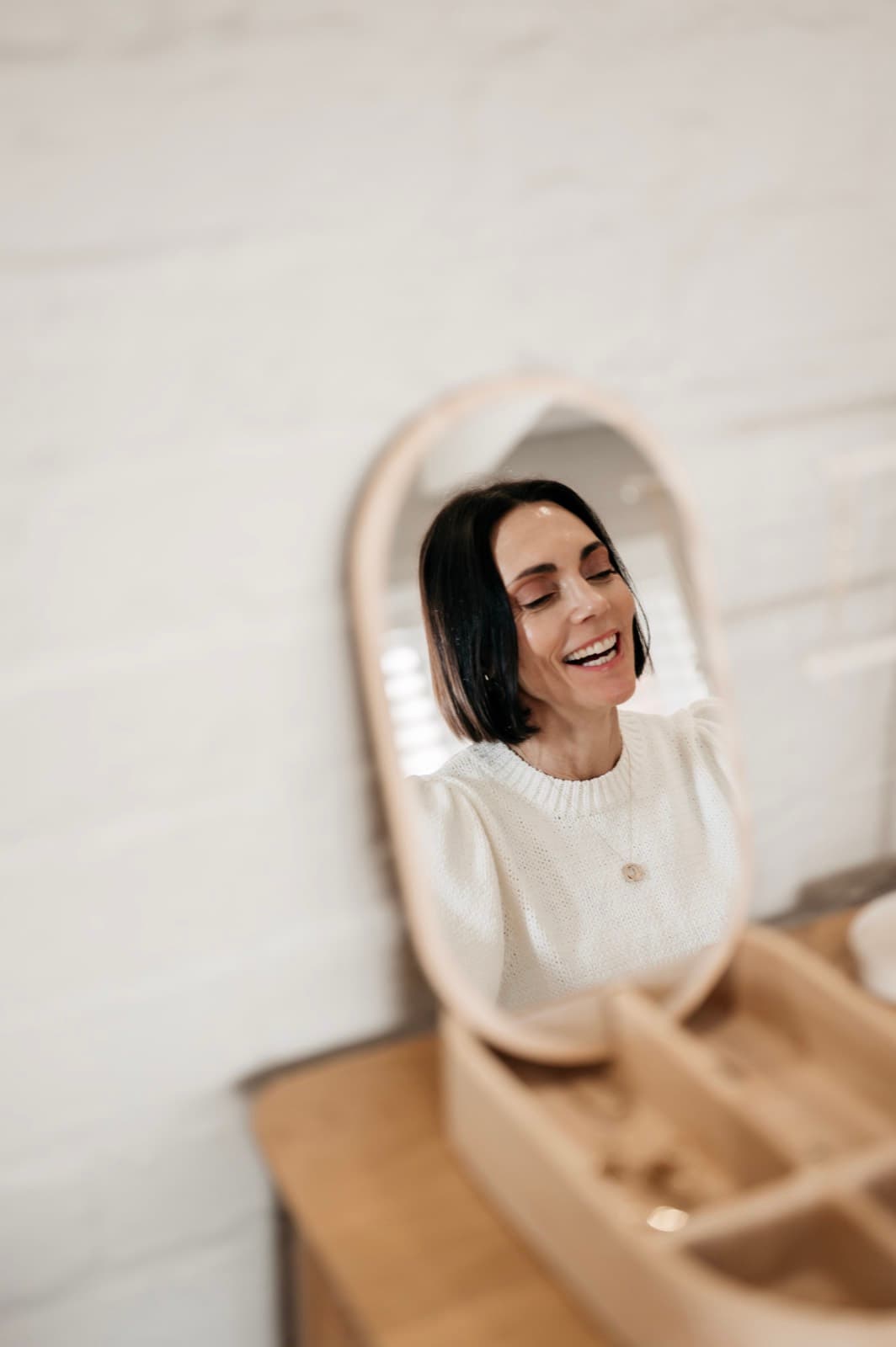 Belinda laughing, reflected in an oval mirror