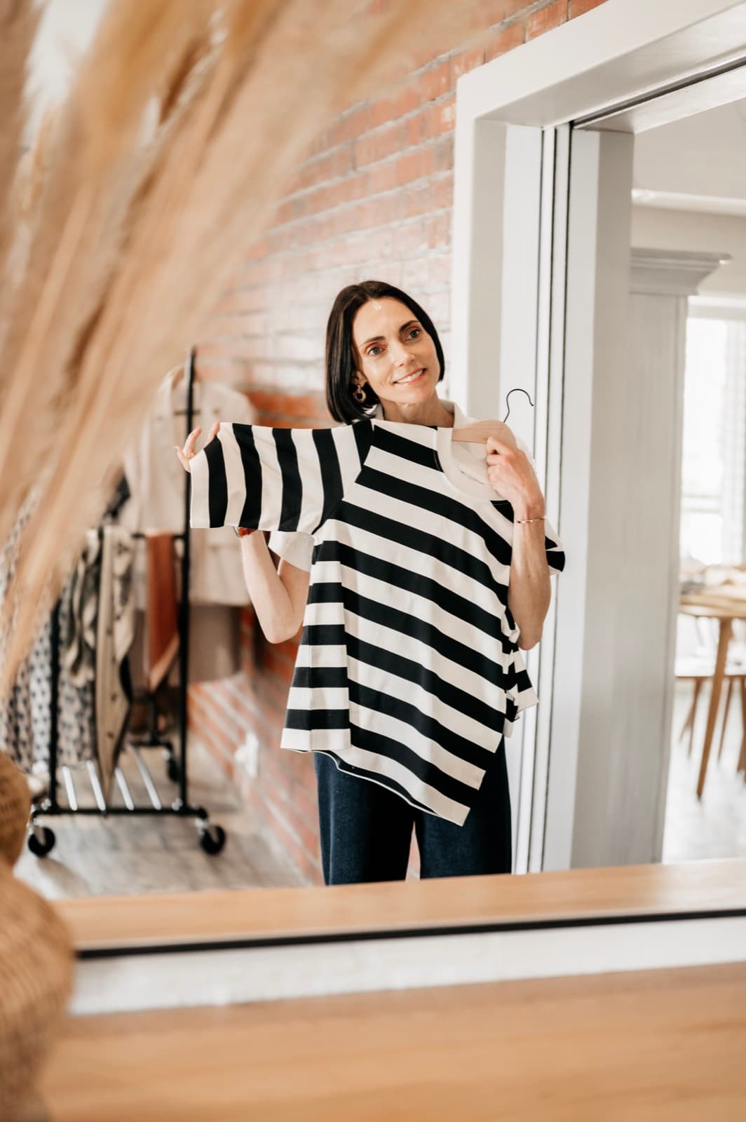 Belinda smiling into a studio mirror in a striped top