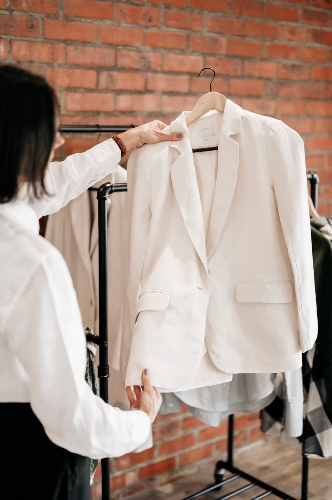 Belinda holding a cream blazer on a hanger at the rack